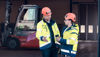 Tvä män i varselkläder och hjälm som pratar med varandra